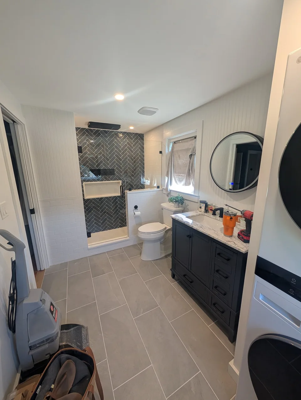 Glass shower and dark vanity; tools are still visible in this project photograph.