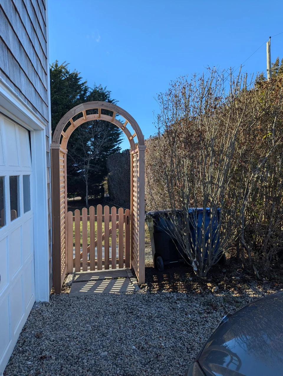 Arched garden arbor and gate beside a house.