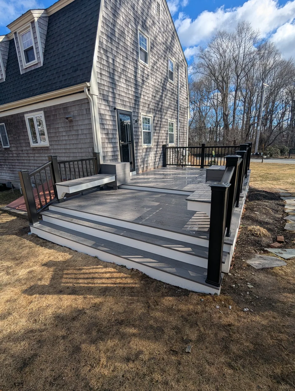 Gray deck with wide steps, black railings, and built-in seating