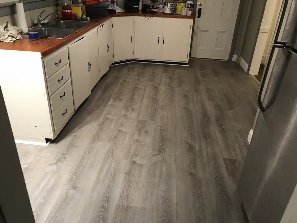 Gray wood-look plank flooring fitted around the existing kitchen cabinets.
