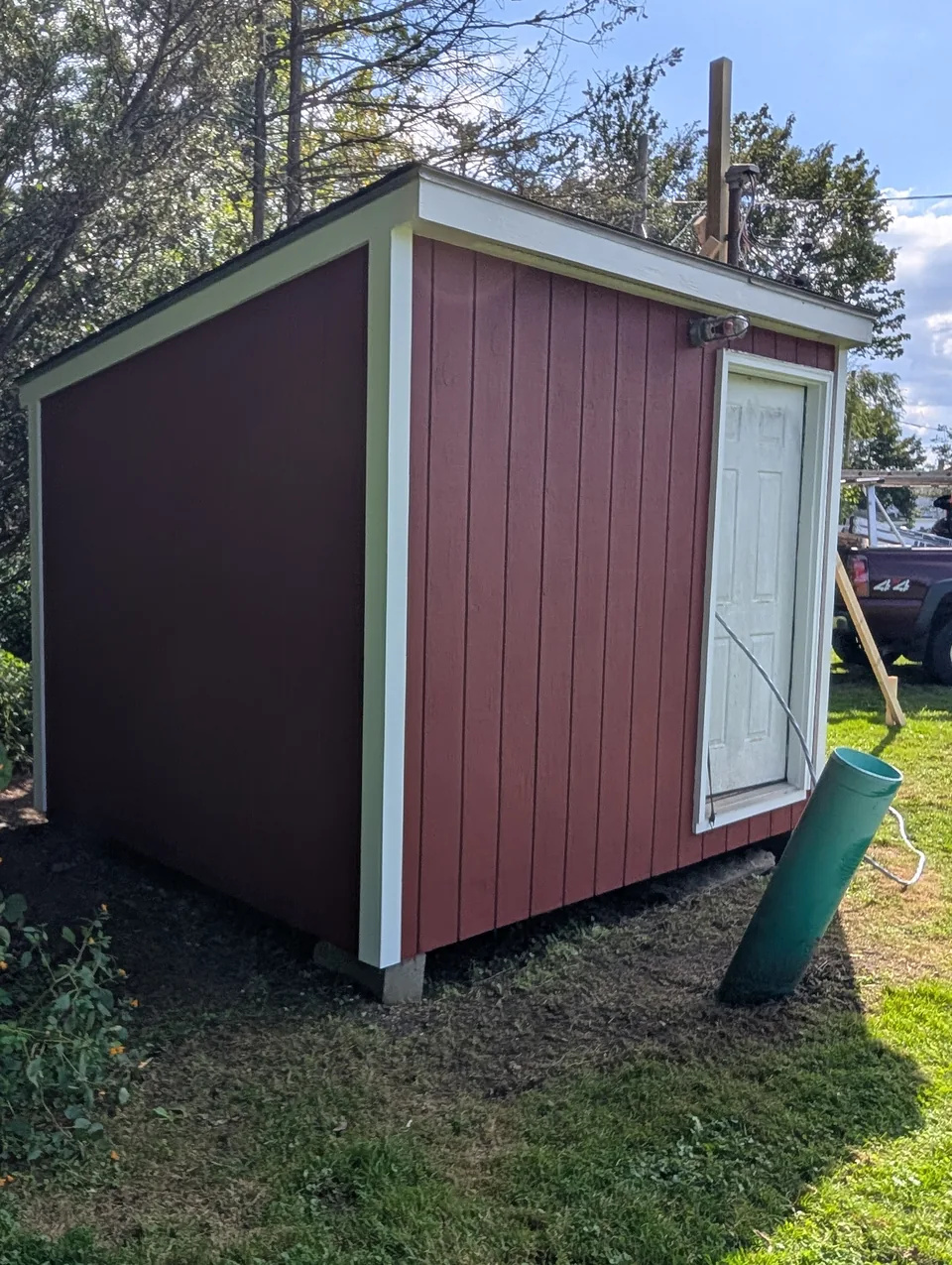 Red outbuilding with white corner and roof-edge trim.